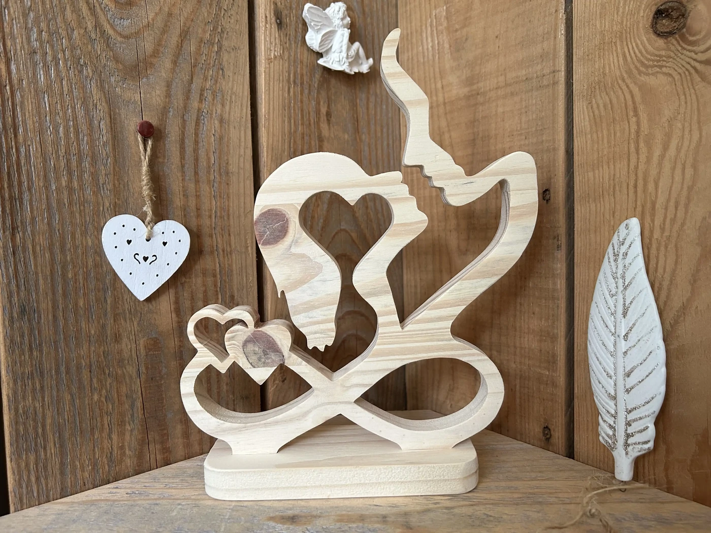 Visages suspendus - L’amour infini, un sentiment si profond et puissant qu'il transcende le temps et l'espace. Cet espace suspendu des visages, telle une force qui unit les cœurs - En bois de pin - Hauteur 24 cm - En stock 25€